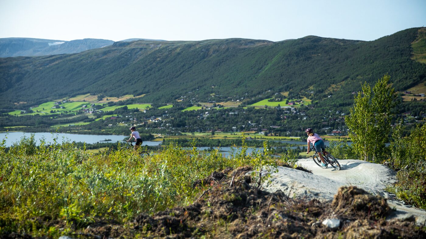 Walkers on a rocky summer trail above a green mountain valley