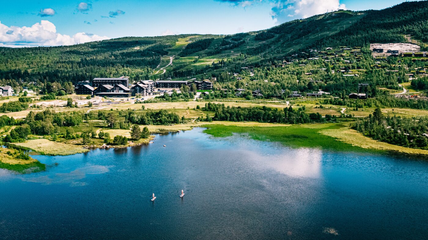 An aerial view of a green resort landscape beside a blue lake