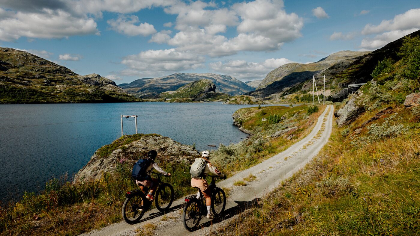 Cyclists on a gravel track beside a mountain lake