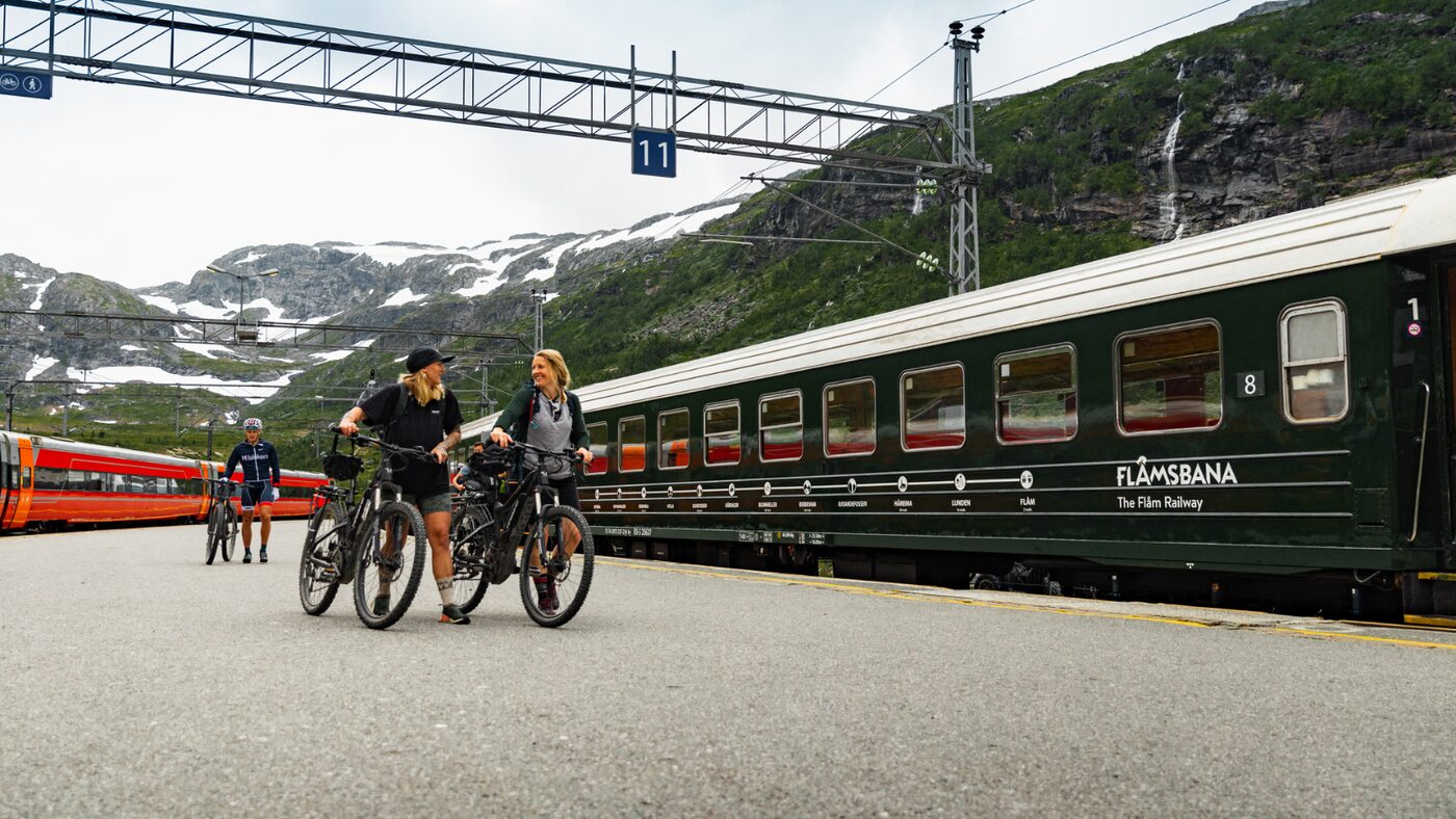 Cyclists with their bicycles beside a train at a mountain railway station